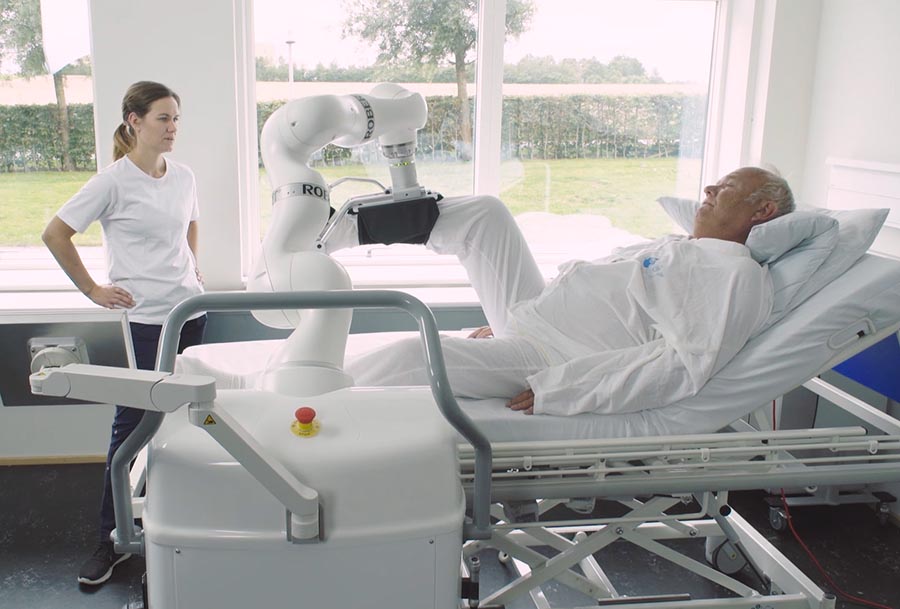 Therapierobotik Robert mobilisiert Patient im Bett als Co-Therapeut mit Therapeutin - Therapieroboter